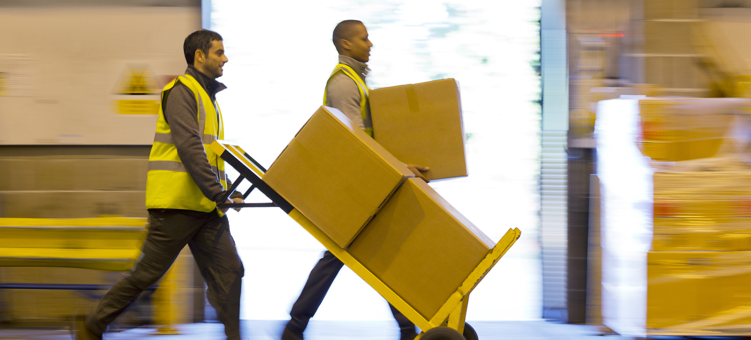 Workers carting boxes in warehouse